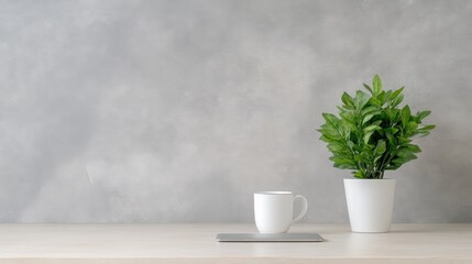 Minimalist workspace with a plant and coffee cup.  Simple, modern aesthetic on a light wooden surface