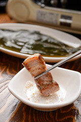 Grilled pork being dipped in salt
