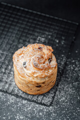 Freshly baked cinnamon roll with icing on a cooling rack in the kitchen