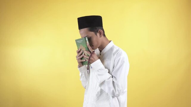 Footage of muslim man wear white shirts with Islamic ornaments close the quran then pay homage to Holy book of Quran