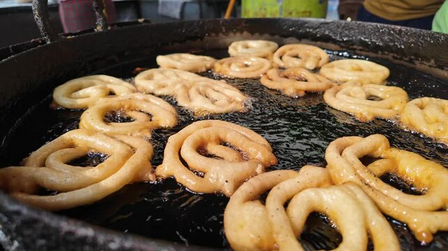 Freshly made jalebi frying in hot oil at local street stall