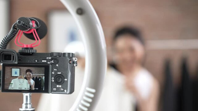 Rear view behide camera screen display woman influencer shoot vlog video review clothes prim social media or blog. Girl with apparel studio lighting for vivancy live streaming marketing recording