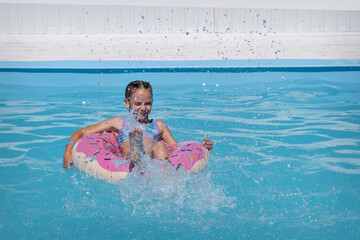 A girl in a swimsuit swims in a perfume circle in the pool, on the beach. Sunset on the shore of the blue sea, a child in a swimsuit. 