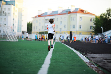 The child goes in for sports at the stadium. The boy is training before playing football.