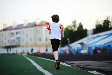 Fototapeta premium The child goes in for sports at the stadium. The boy is training before playing football.