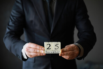 Portrait of  businessman ready for Christmas. Wooden cubes with inscription 25 december