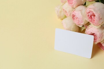 Obraz premium Beautiful pink peony roses with paper card on color background