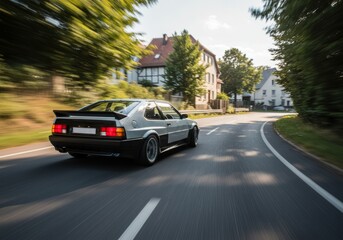 Vintage Silver Car Driving Fast on Road with Trees and Houses