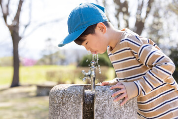 公園の水道で水を飲む男の子