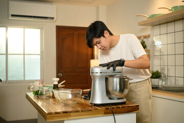 Young asian man preparing whipped cream with a stand mixer in home kitchen