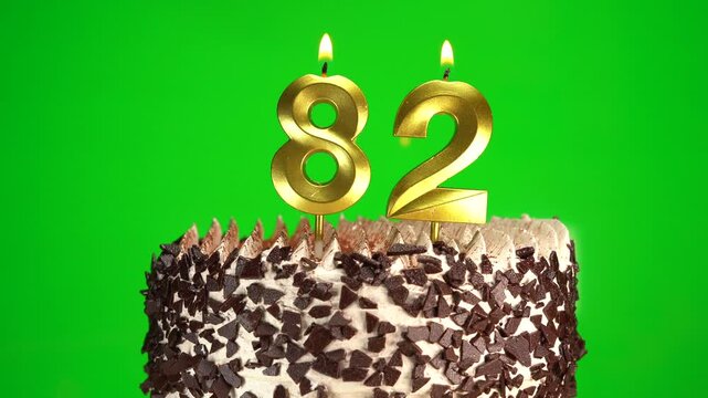 Burning candles number 82 on birthday cake against chroma key background. Eighty-second birthday. Birthday celebration