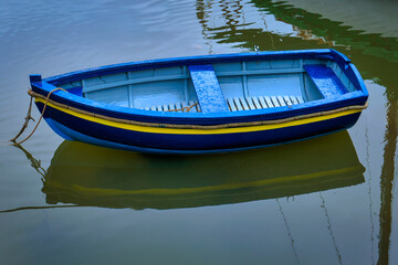 barque en bois bleue se reflétant sur une eau calme
