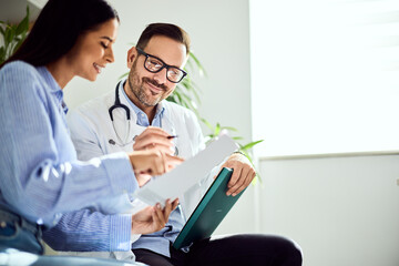 Doctor Discussing Health Report with Smiling Female Patient in Comfortable Setting
