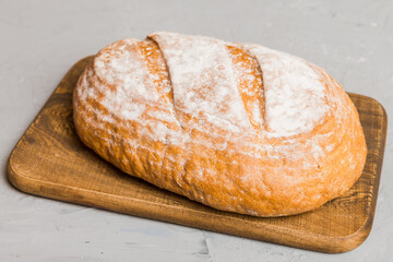 Freshly baked bread on cutting board against white wooden background. perspective view bread with copy space