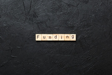 funding word written on wood block. funding text on table, concept
