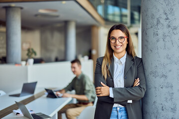 Confident Businesswoman Smiling in Modern Office Environment with Colleagues Working Nearby