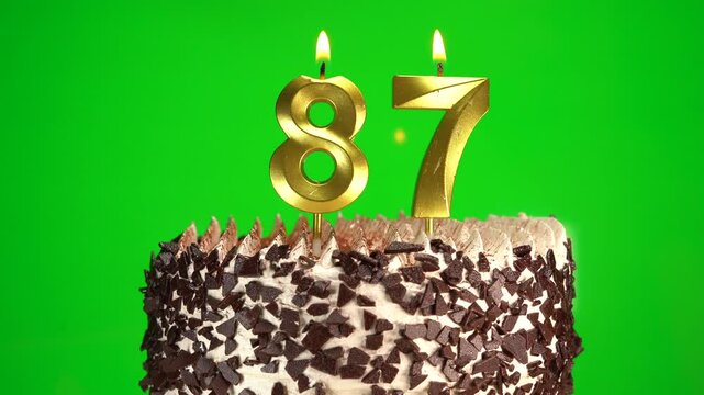 Burning candles number 87 on birthday cake against chroma key background. Eighty-seventh birthday. Birthday celebration