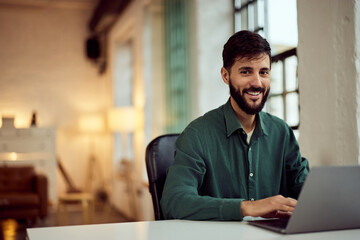 Smiling Professional Man in a Modern Office Working on a Laptop