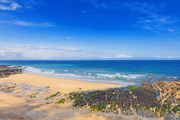 Obraz premium Aerial view at a sand beach with breaking waves and a view over the sea