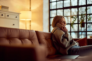 Smiling Woman Enjoying a Phone Call While Relaxing on a Leather Couch