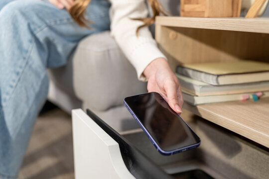 Close up of young attractive woman putting phone in drawer in house. 