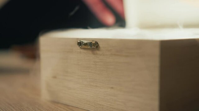 A cinematic close-up shot of a light-colored handcrafted wooden box slowly opening, revealing a mysterious shining light and soft haze flowing out from inside. 4K