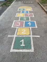 Colorful hopscotch game painted on asphalt in playground, outdoor childhood activity, classic kids street game with numbers and colors