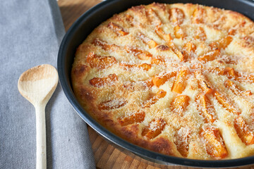 Homemade apricot pie in a baking dish on a wooden table