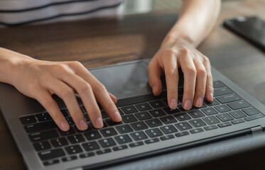 Hands typing keyboard on laptop with working online.
