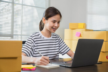 Young Asian businesswoman working talking to customers from order online and packing on the box.
