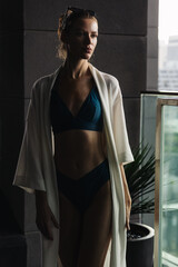 Tanned girl in swimsuit and robe on holiday in hotel. Cinematic evening light.