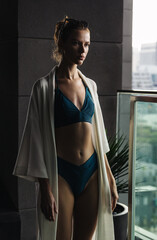 Tanned girl in swimsuit and robe on holiday in hotel. Cinematic evening light.