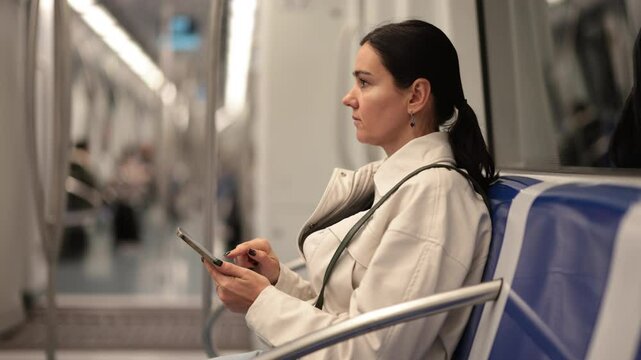 Female passenger moves around city in public transport, passenger rides on half-empty metro carriage. Bored passenger whiles away time on social media