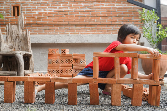 Little Builder girl is learning how to build brick wall in vintage tone 
