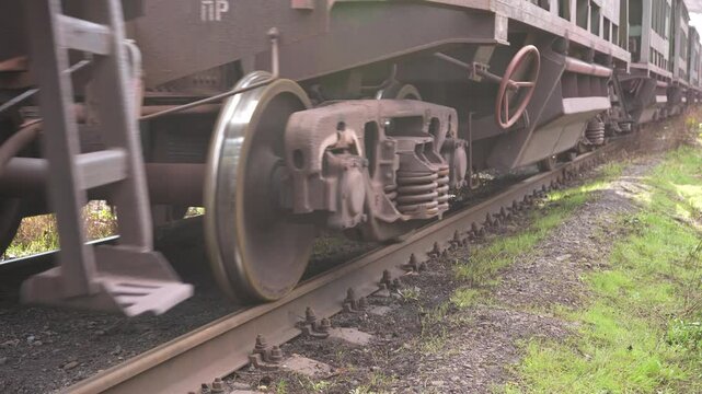 Close-up of freight train rolling stock. Low-angle close-up of steel freight car wheels rattling on concrete sleepers. Loaded hopper cars moving. High quality 4k footage