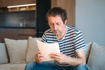 Man reading instruction manual paper at home
