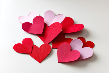 Colorful paper hearts scattered on a white surface.