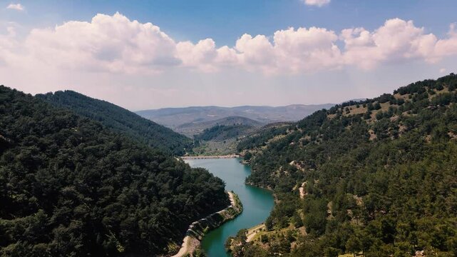 Stunning aerial view of a picturesque valley with a serene lake nestled amidst lush green mountains in Torbali, near Izmir