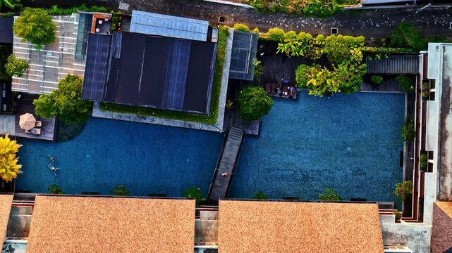Resort complex with blue pools on coastline of Bali, aerial top down view