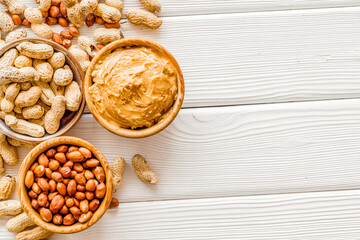Make peanut butter with nuts and paste in bowl on white wooden b