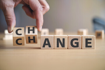 Hand arranging wooden cubes spelling "change", representing transformation, progress, and adaptation concepts in business or life