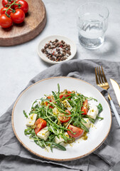 Healthy arugula salad with cherry tomatoes, mozzarella and pesto sauce on a plate