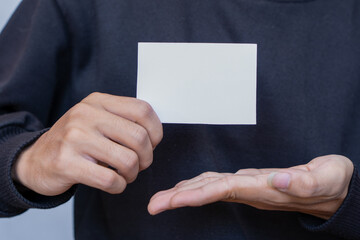 A man wearing a black shirt holding white blank business card mockup