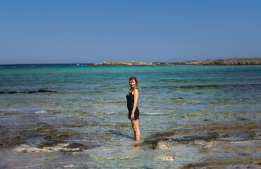 the woman enters the clear water in a black dress to cool off