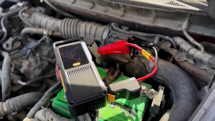 Capture the essence of automotive preparedness with a 4K shot of a jump starter charging a battery. Perfect for tutorials, ads, or automotive guides.