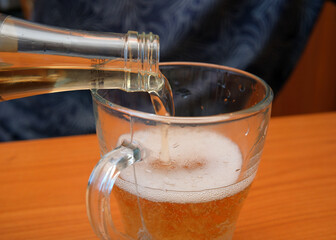 Pouring refreshing beverage into a glass at sunset
