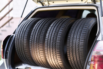 Four summer tires placed in open car trunk