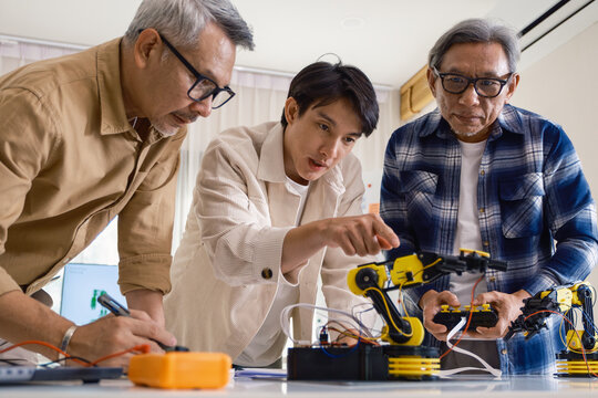 asian Robot arm engineers brainstorming in workshop to develop control technology with teamwork and coding innovation