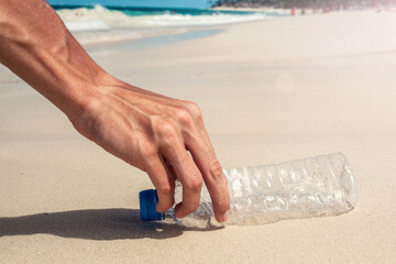 volunteer collects plastic bottles from the ocean shore