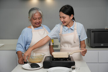 Two women, daughter cooking with elderly mother at home, happy mother's day, family day